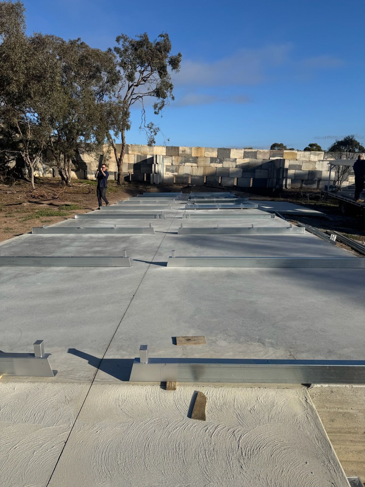 A man is walking down a concrete road with trees in the background.
