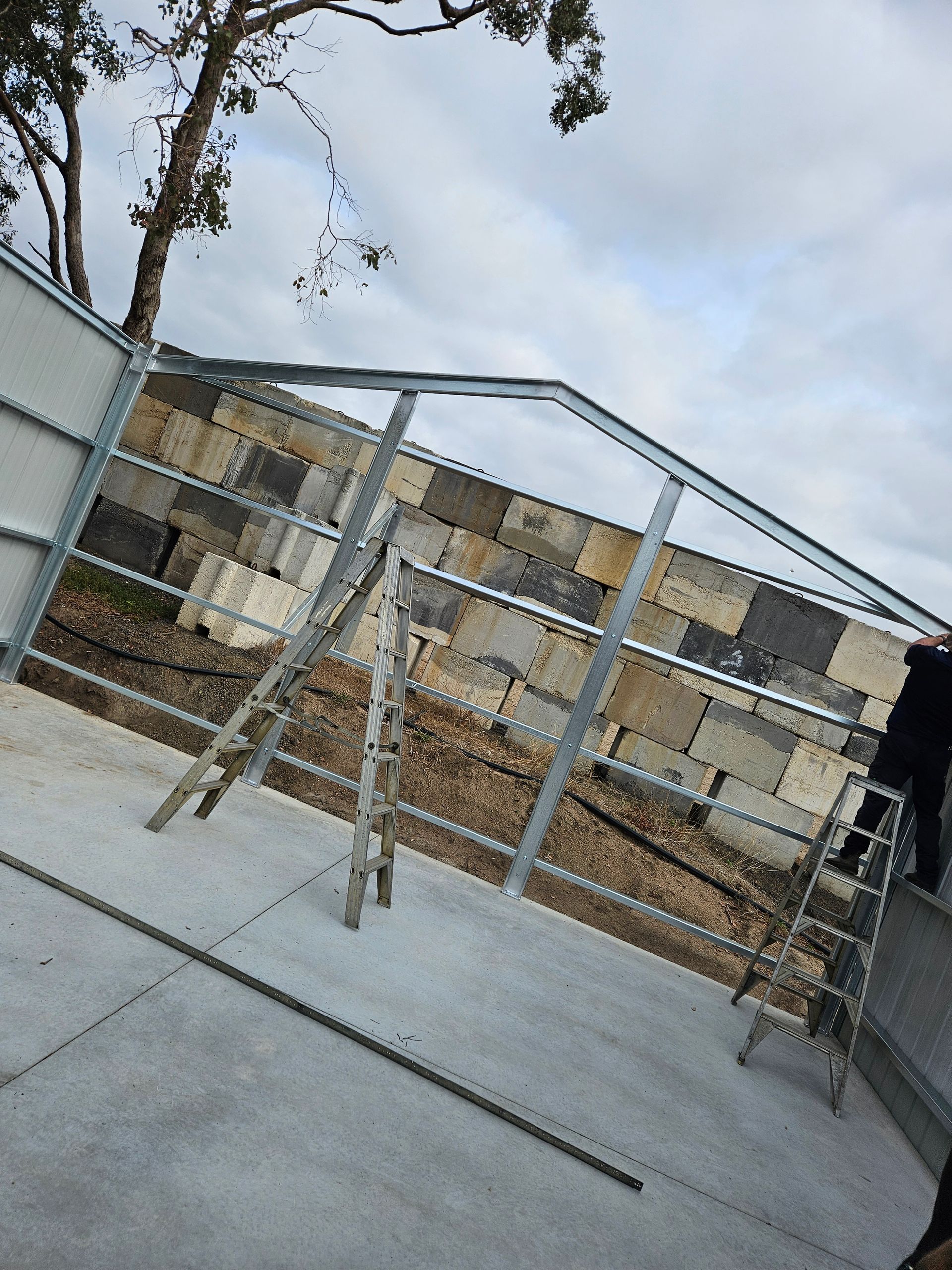 A person is standing on a ladder in front of a metal structure.