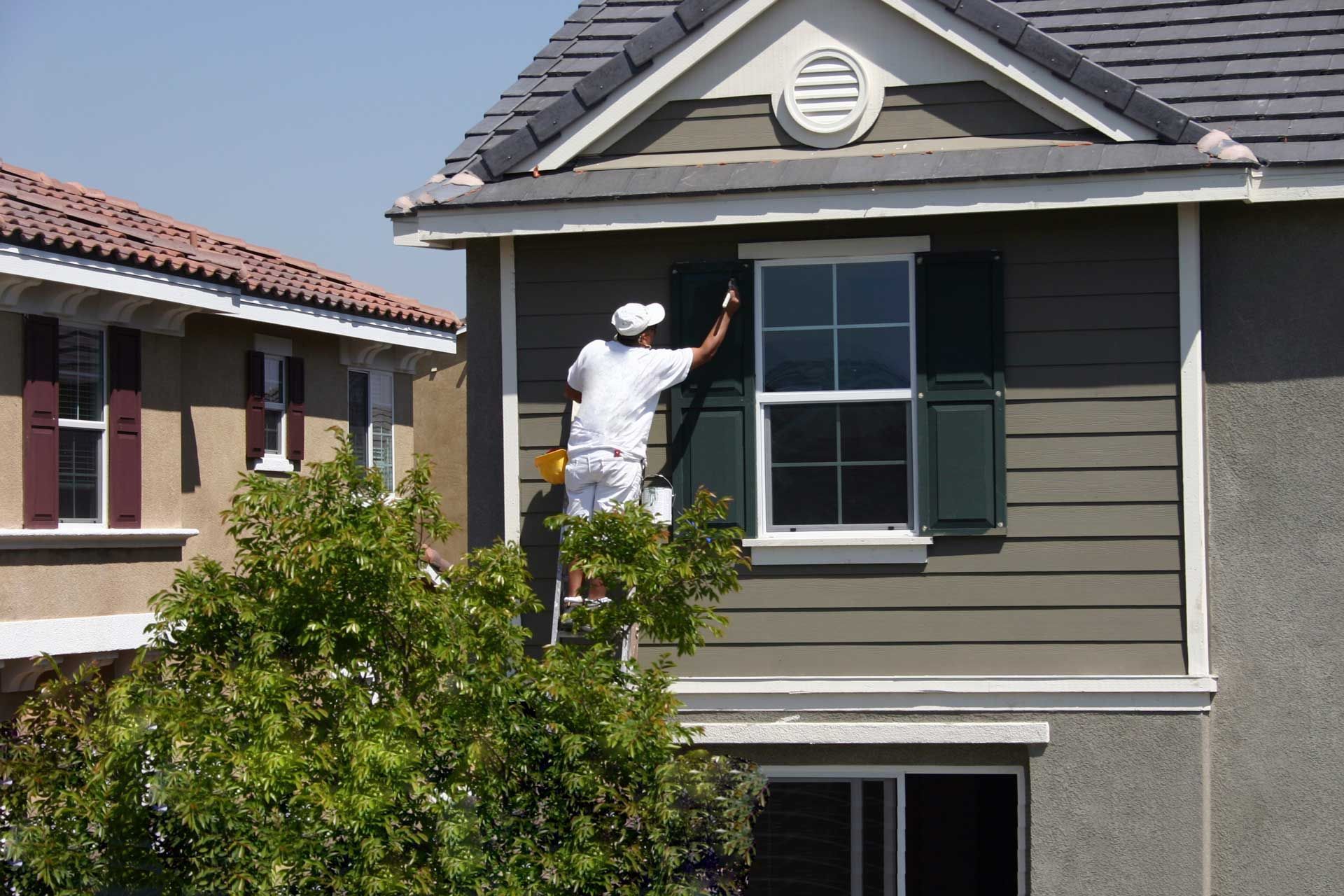 A man is painting the side of a house A man is painting the side of a house