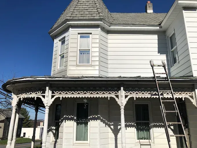 A white house with a ladder on the porch.