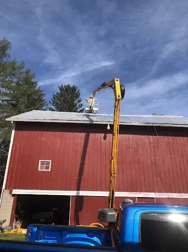 A blue truck is parked in front of a red barn.