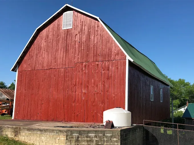 A red barn with a green roof and white trim