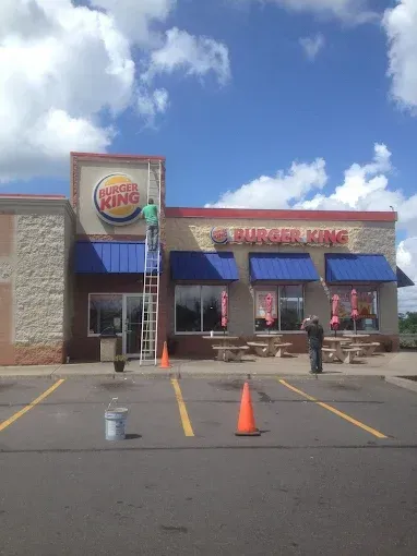 A burger king restaurant is being painted on a sunny day.