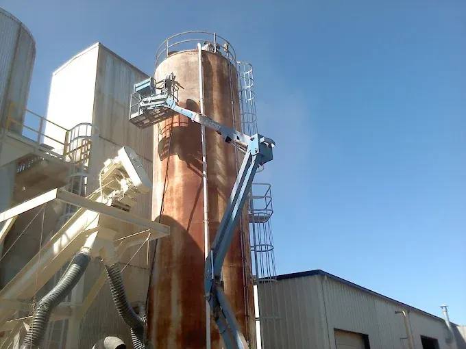 A crane is being used to clean a silo in a factory