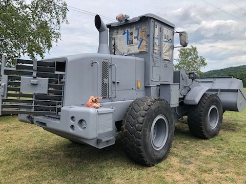 A large gray tractor is parked in a grassy field. A large gray tractor is parked in a grassy field.