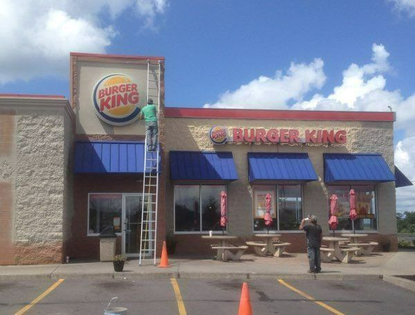 A man on a ladder painting a burger king sign A man on a ladder painting a burger king sign