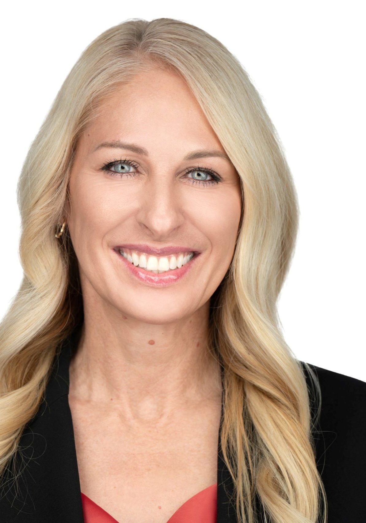 Woman with blonde hair smiles, wearing a black blazer and red top.