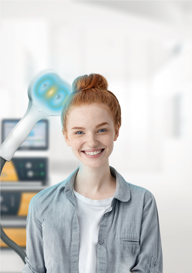 Foto de uma paciente sorrindo com uma máquina utilizada no tratamento de Estimulação Magnética ao fundo