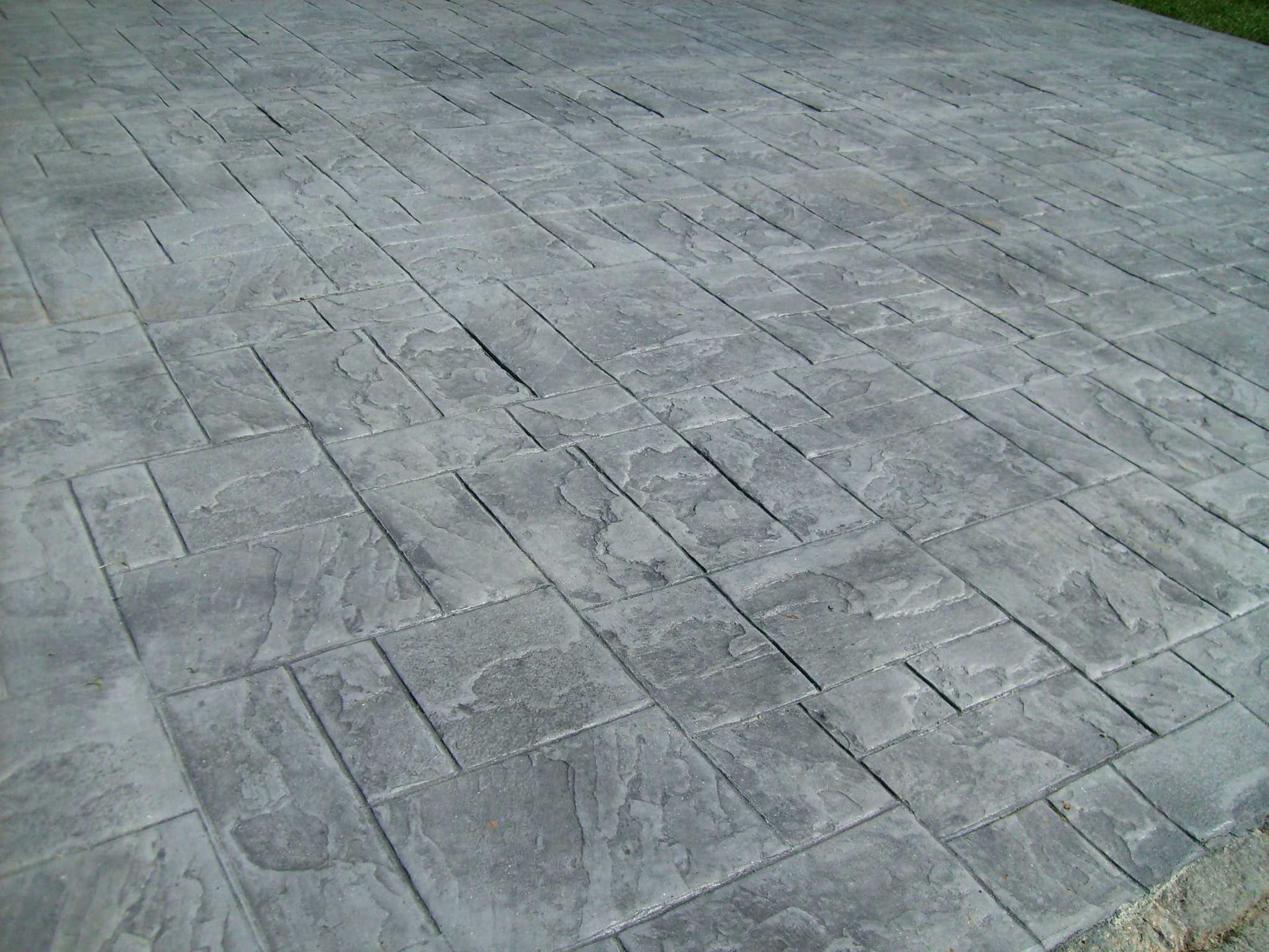 Stamped concrete driveway with a gray, brick-like pattern.
