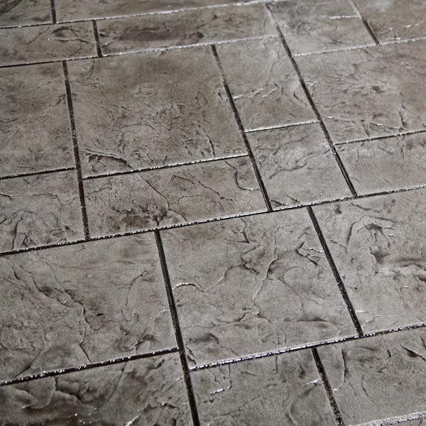 Gray stamped concrete patio with rectangular and square stone patterns.