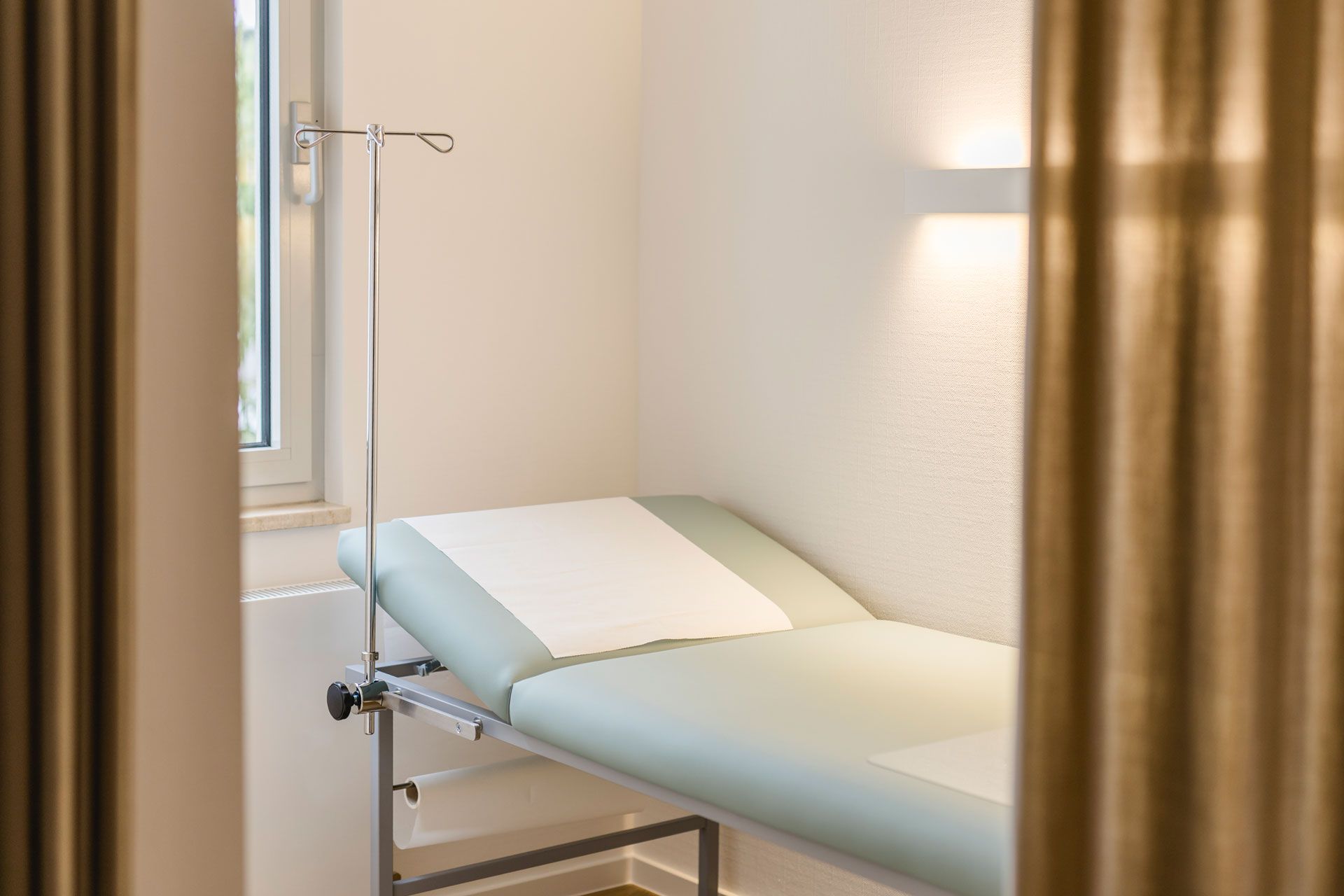 Behandlungszimmer mit einem braunen Vorhang und einer Liege