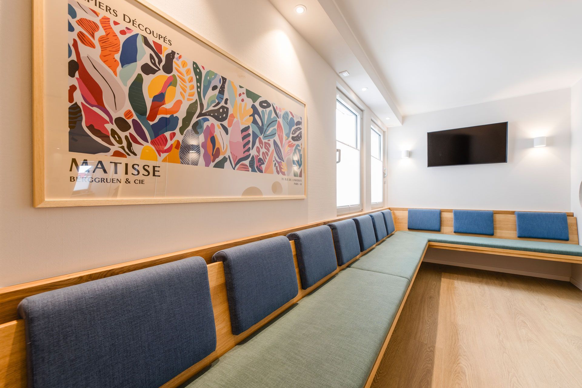 Wartezimmer, eine Sitzbank mit blauen Polstern, Matissebild an der Wand 