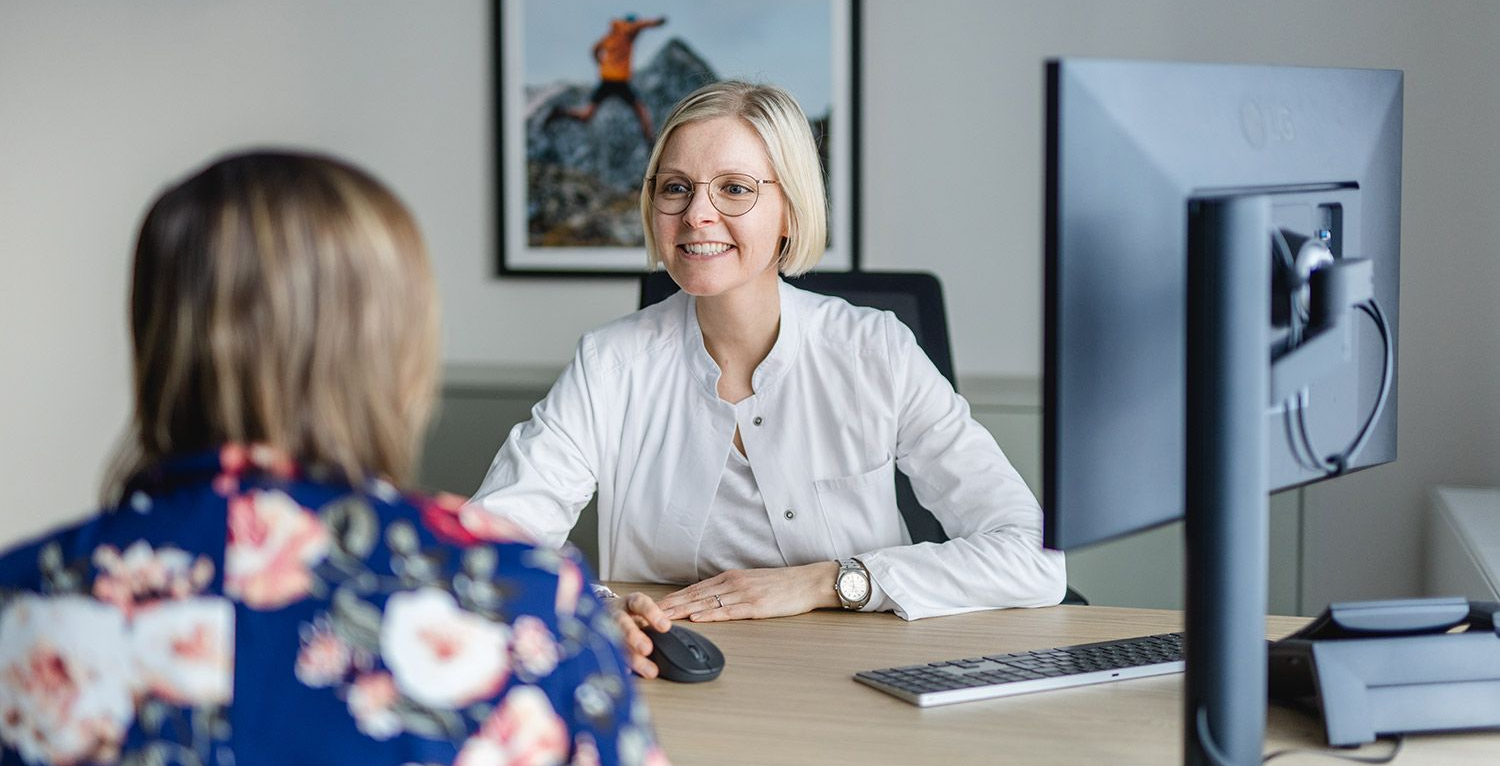 Ärztin füllt ein Formular aus, Patientin sitzt dabei