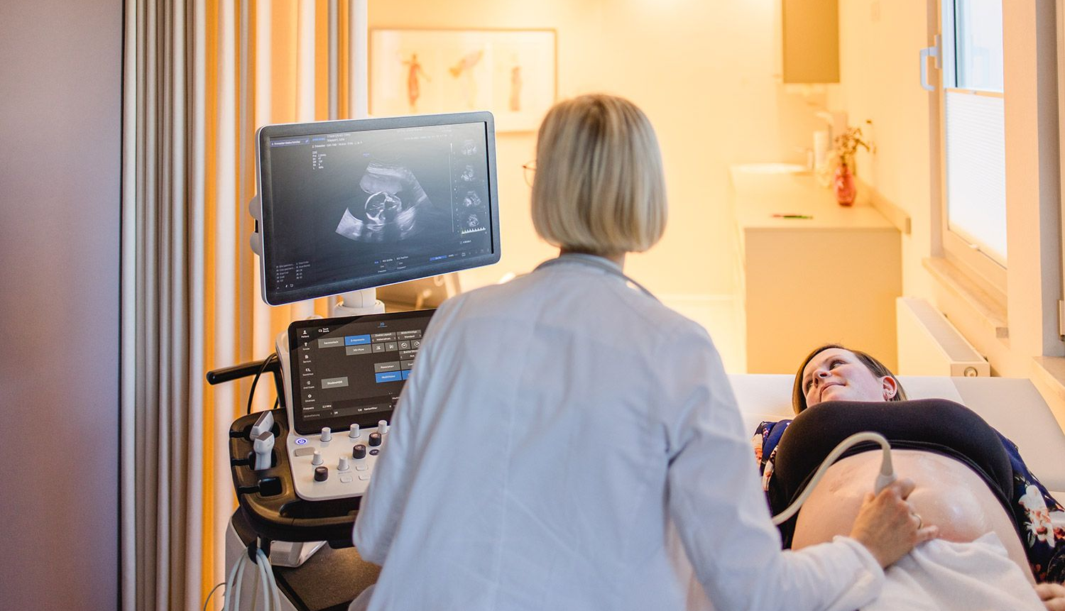 Eine Schwangere wird mit einem Ultraschallgerät am Bauch untersucht