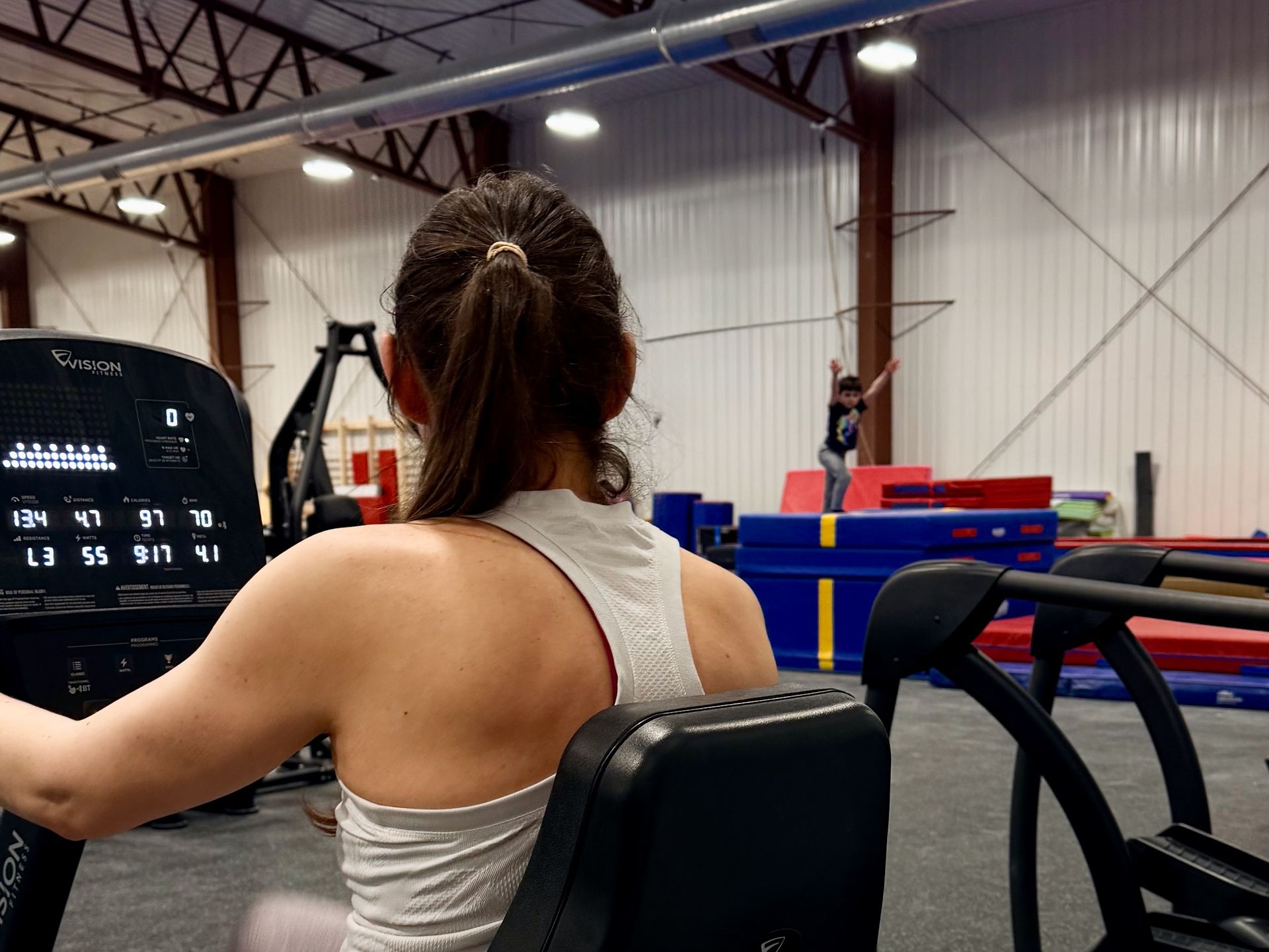 Child in red shirt using an elliptical machine in a gym