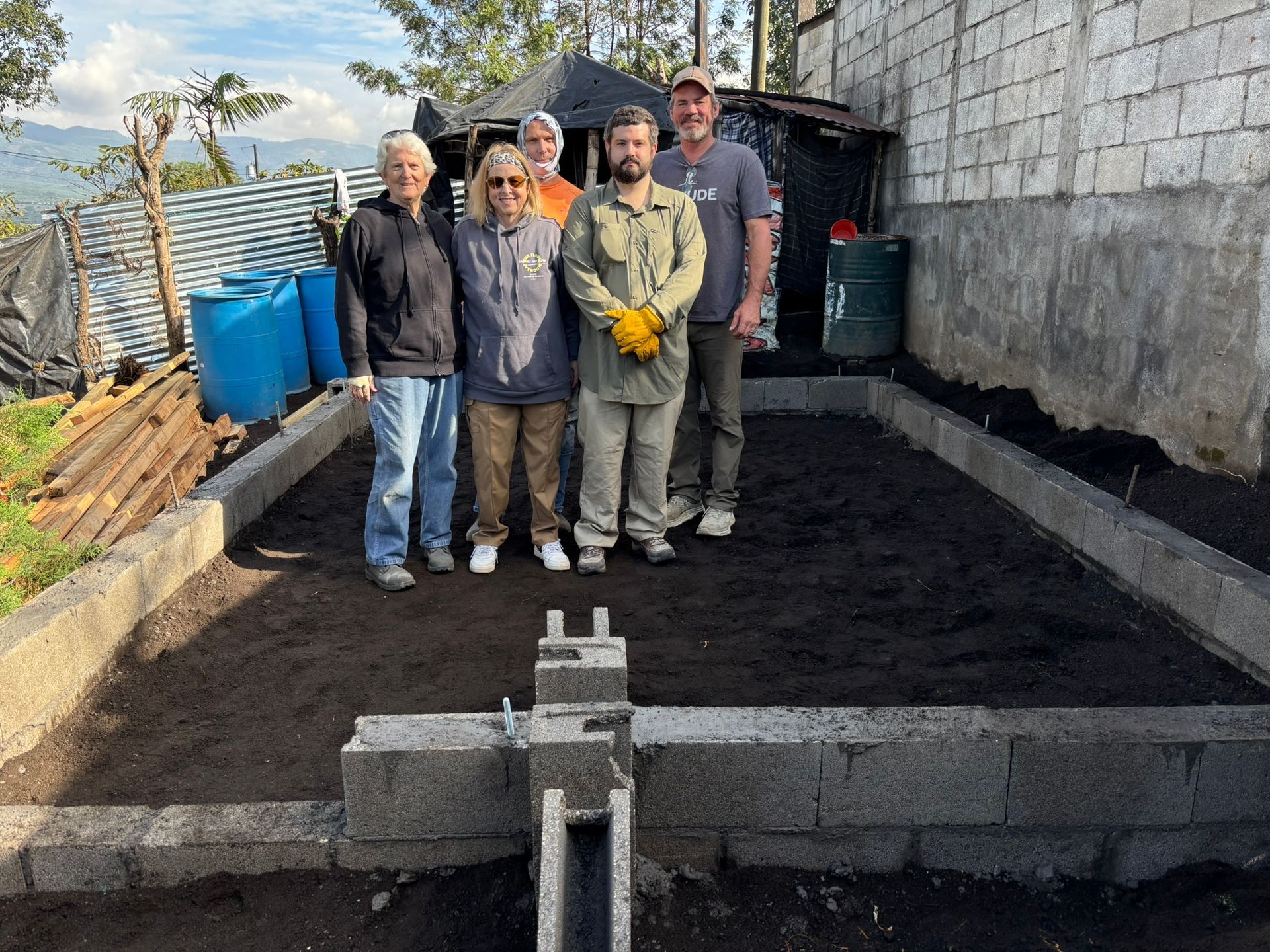 A group of people are standing in front of a brick wall.