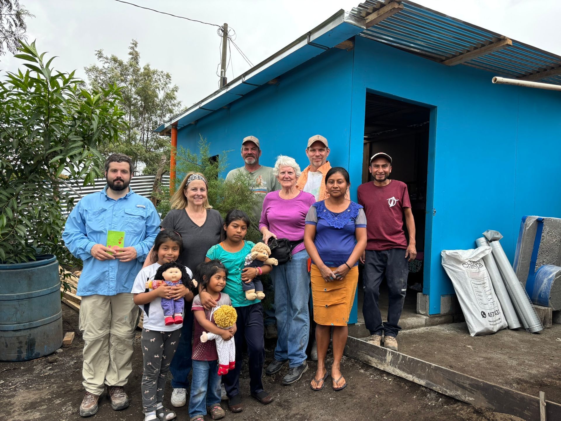 A group of people are posing for a picture in front of a blue house.