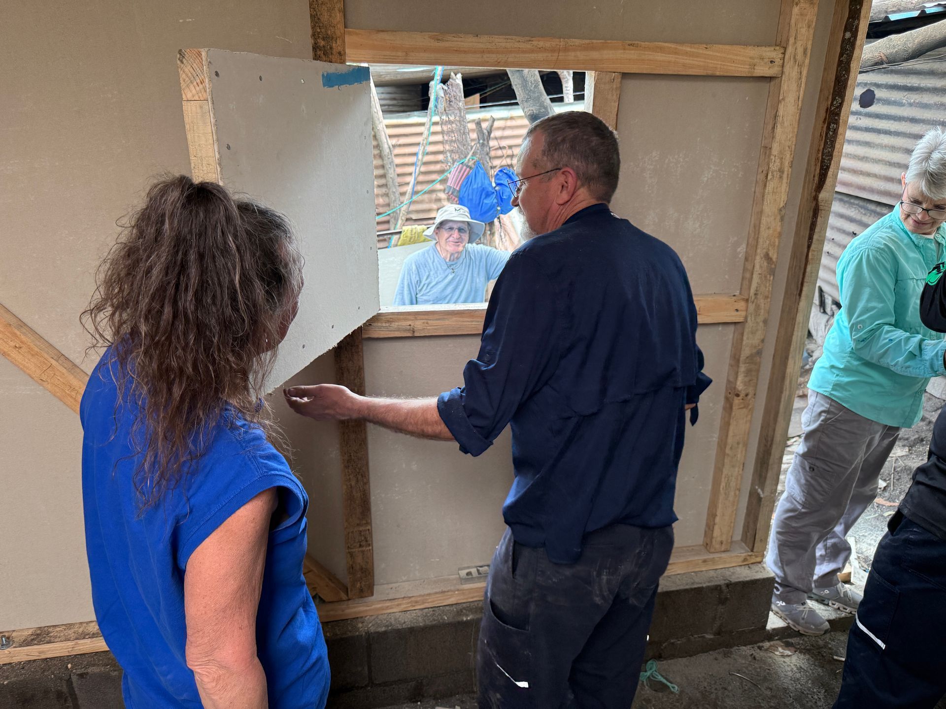A man and a woman are standing in front of a window.