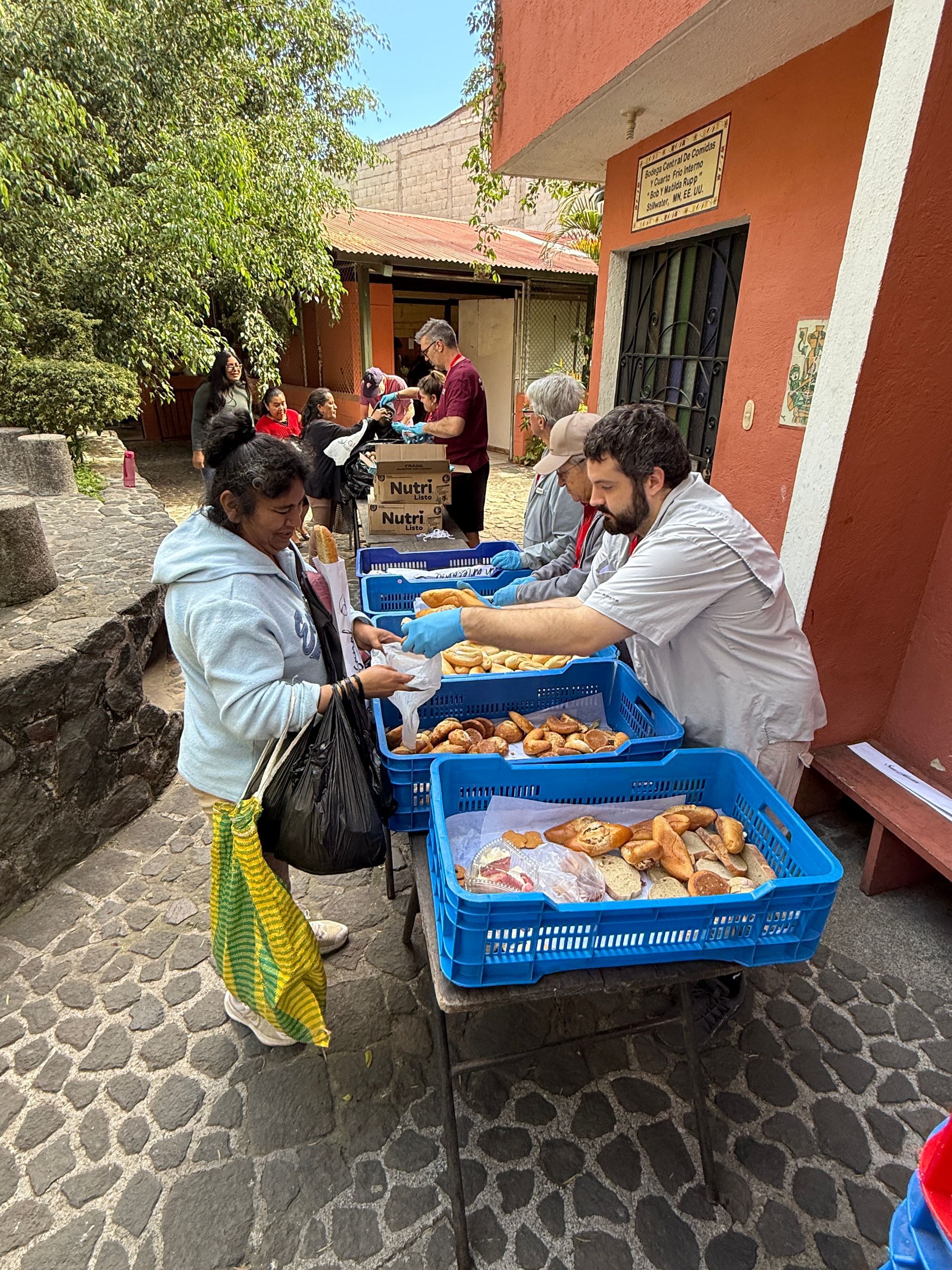 A group of people are standing around a table with trays of food.