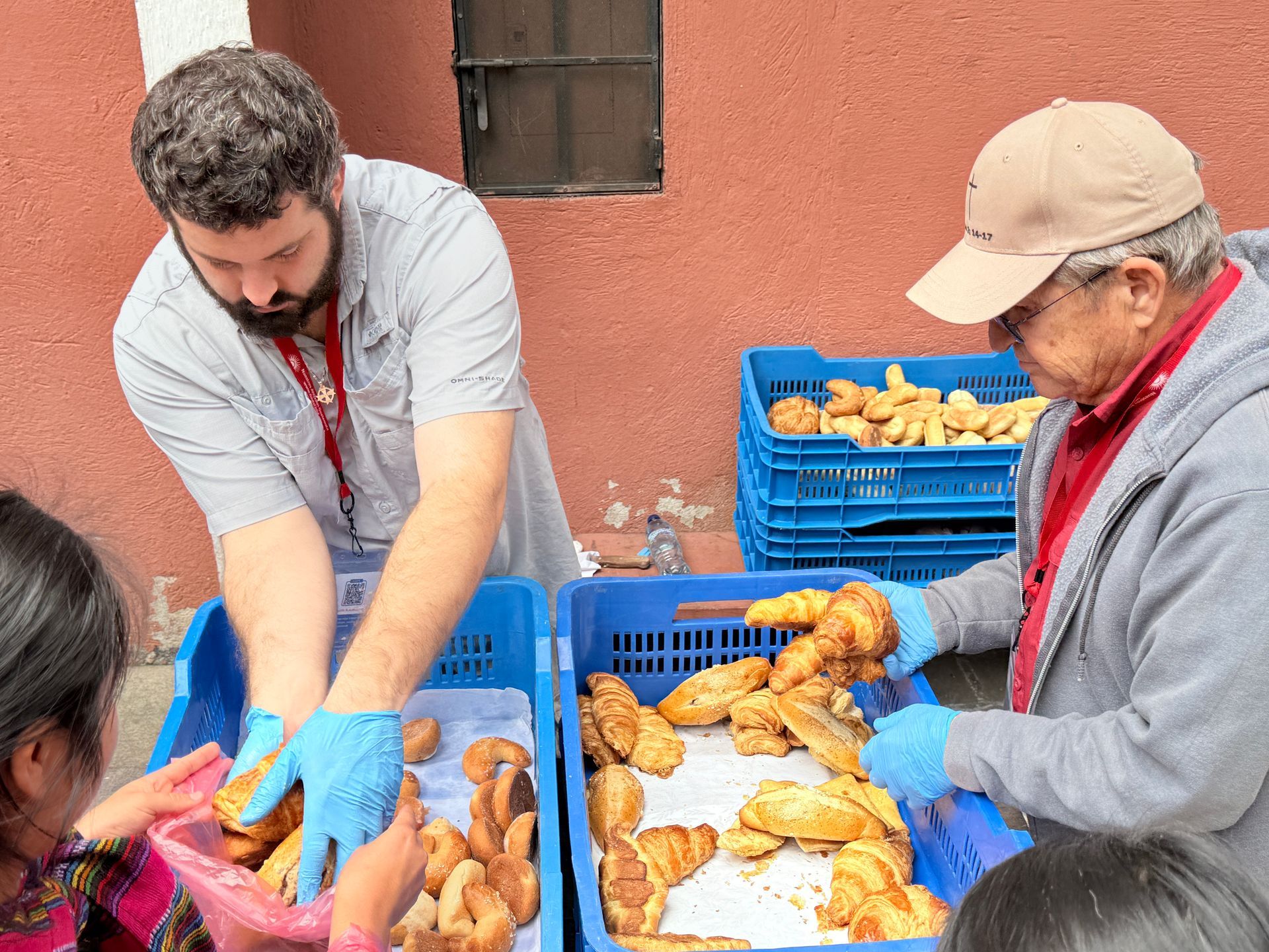 Two men are working on a tray of bread outside