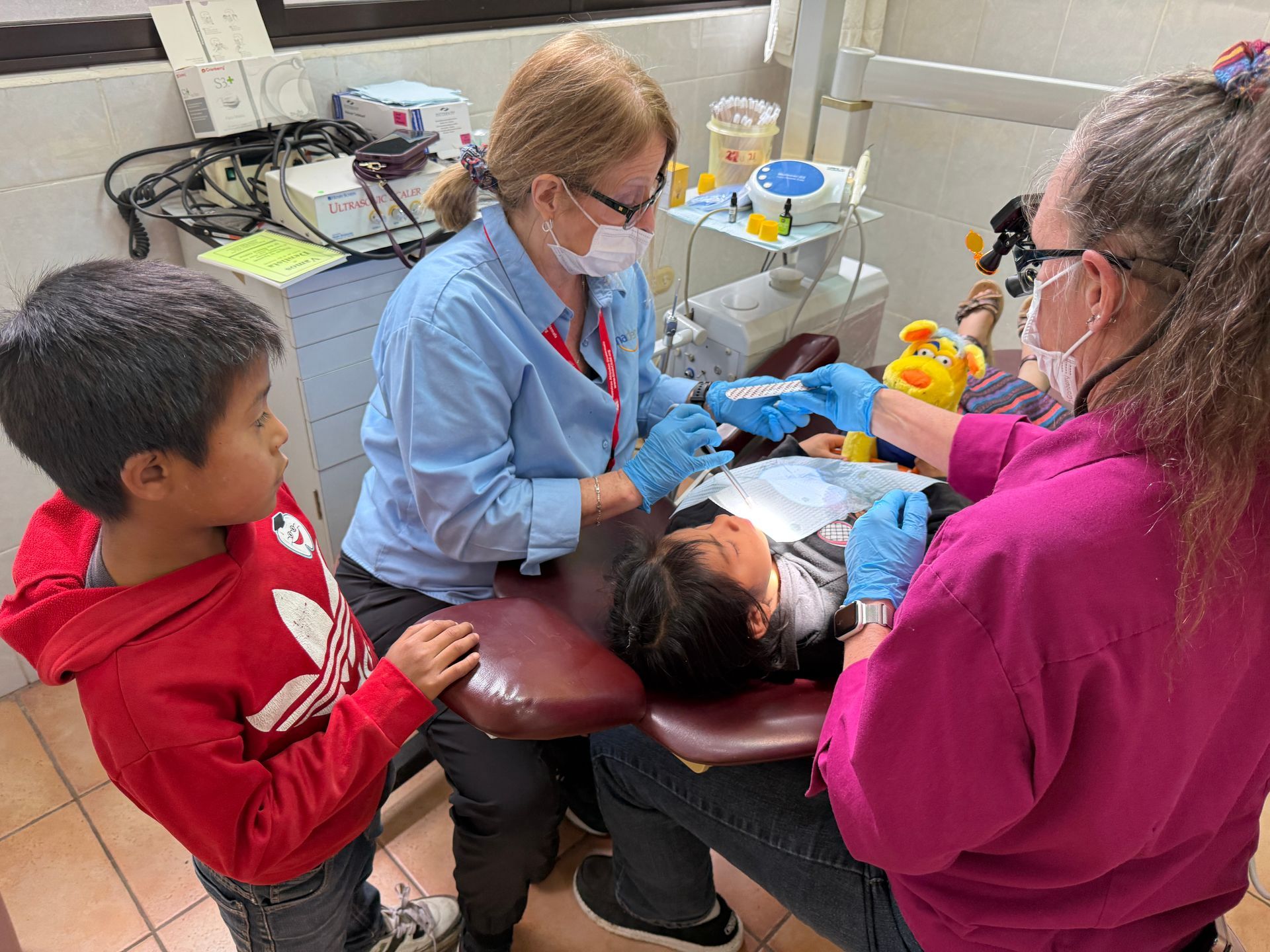 A dentist is examining a child 's teeth in a dental office.