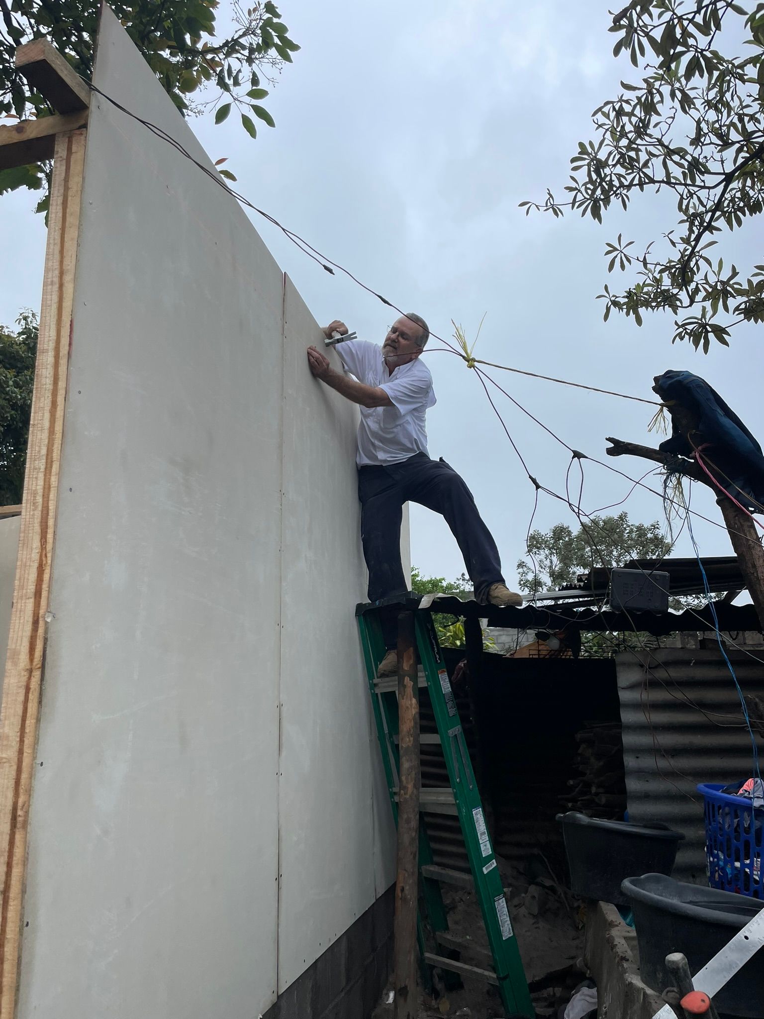 A man standing on a ladder working on a wall