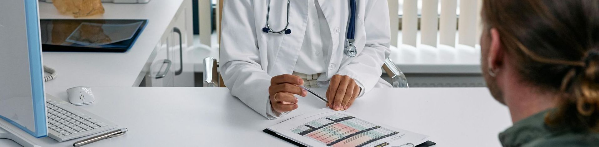 A doctor is talking to a patient at a desk in a hospital.