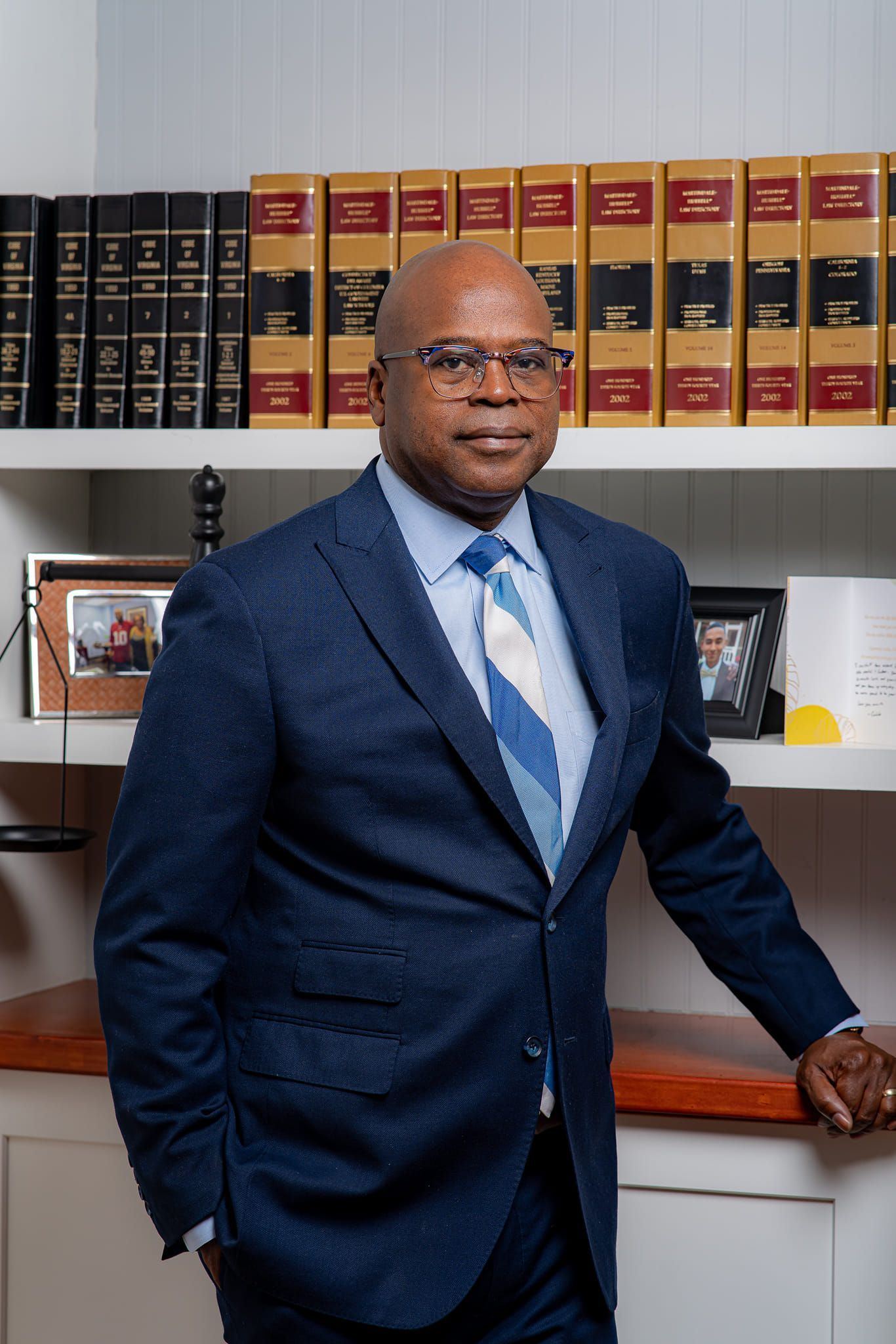 A man in a suit and tie is standing in front of a bookshelf filled with books. A man in a suit and tie is standing in front of a bookshelf filled with books.