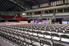 Rows of folding chairs are lined up in an empty stadium.