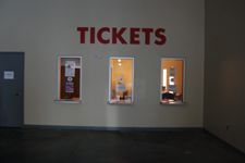 A building with three windows and a sign that says tickets on it.