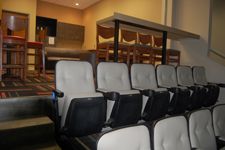 A row of empty chairs in an auditorium with stairs leading up to them.