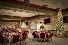 A large room filled with tables and chairs and a christmas tree.