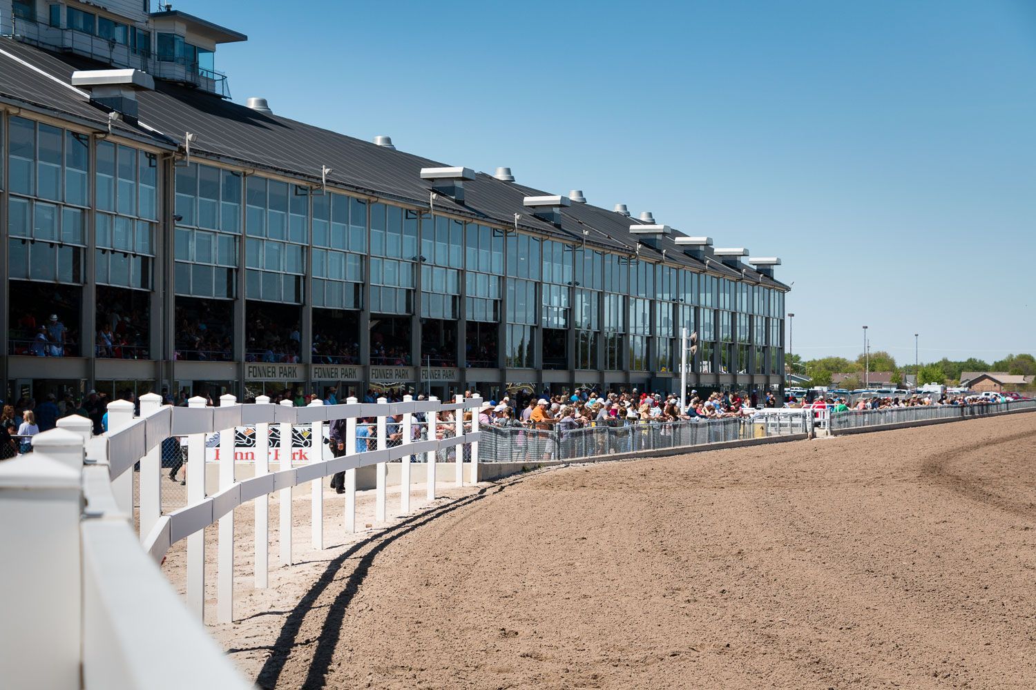 A race track with a white fence and a building in the background.