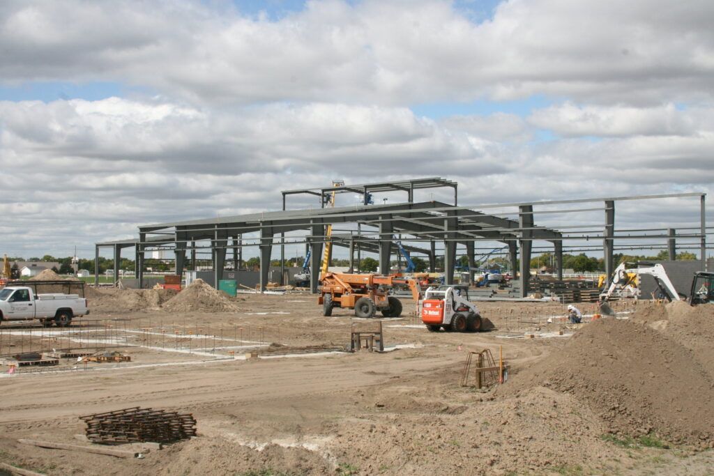 A large building is being built in the middle of a dirt field.