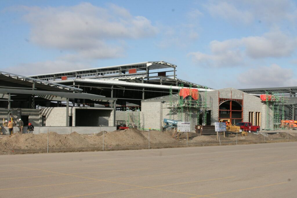 A large building is being built in the middle of a dirt field.