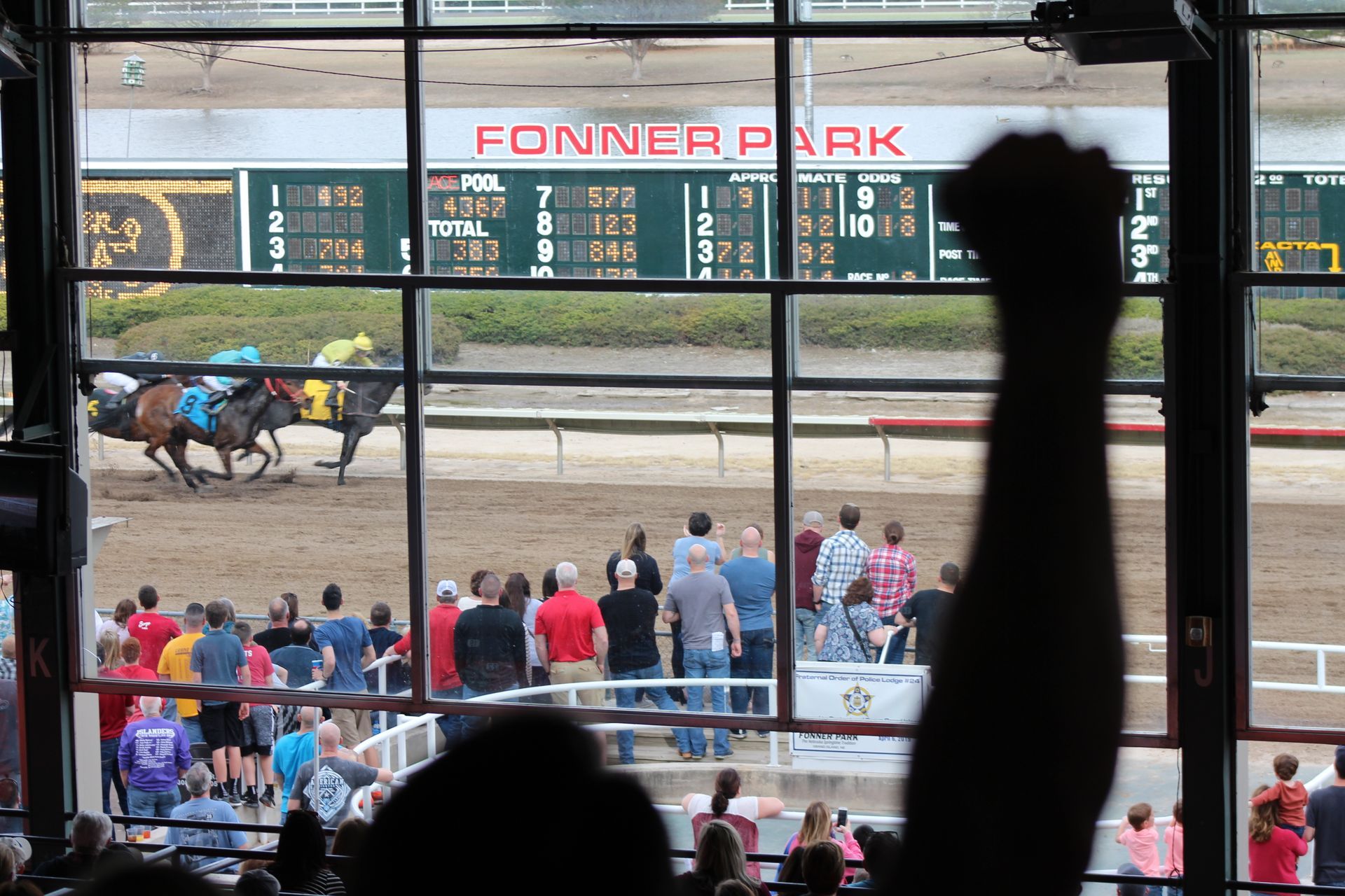 A crowd of people watching a horse race at fonner park