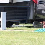 A rv is parked in a grassy field next to a white pole.