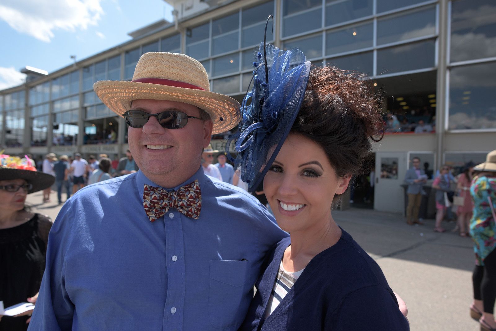 A man and a woman are posing for a picture at a race track.