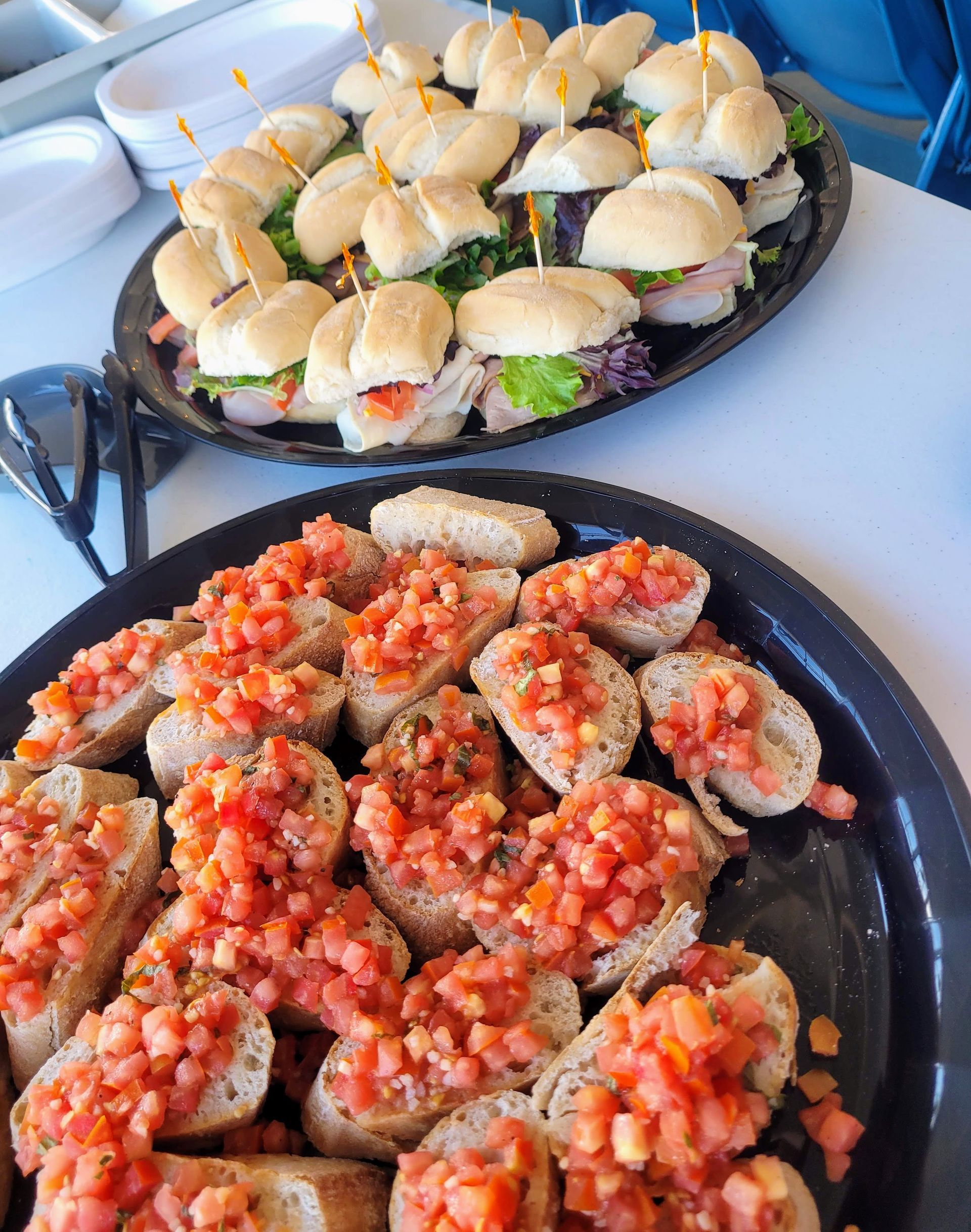 Two plates of food with sandwiches and tomatoes on them are on a table.