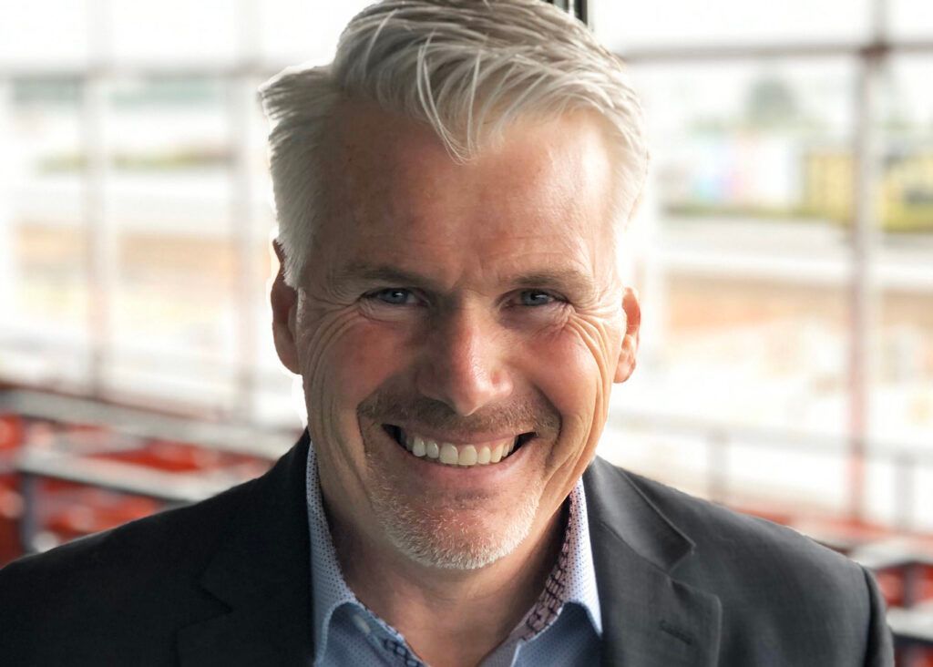 A man in a suit and blue shirt is smiling for the camera.