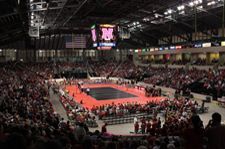 A large crowd of people are watching a wrestling match in a stadium.