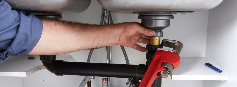 Plumber at work under a sink unit