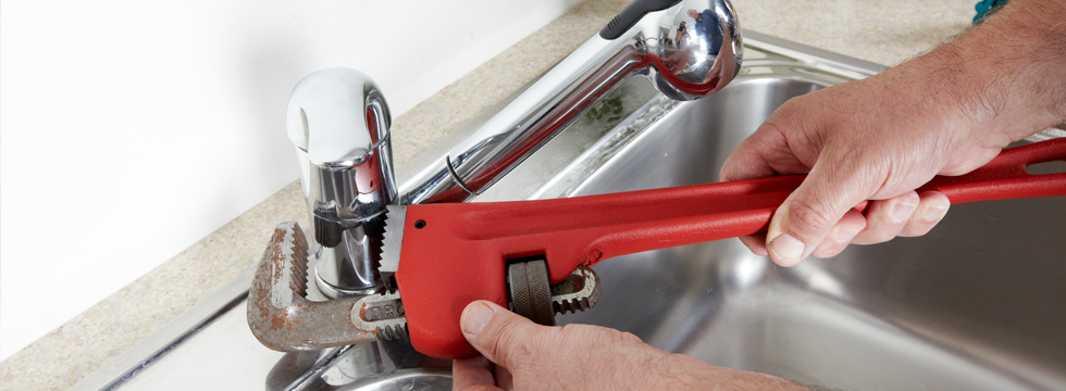 Plumber's wrench on a chrome mixer tap