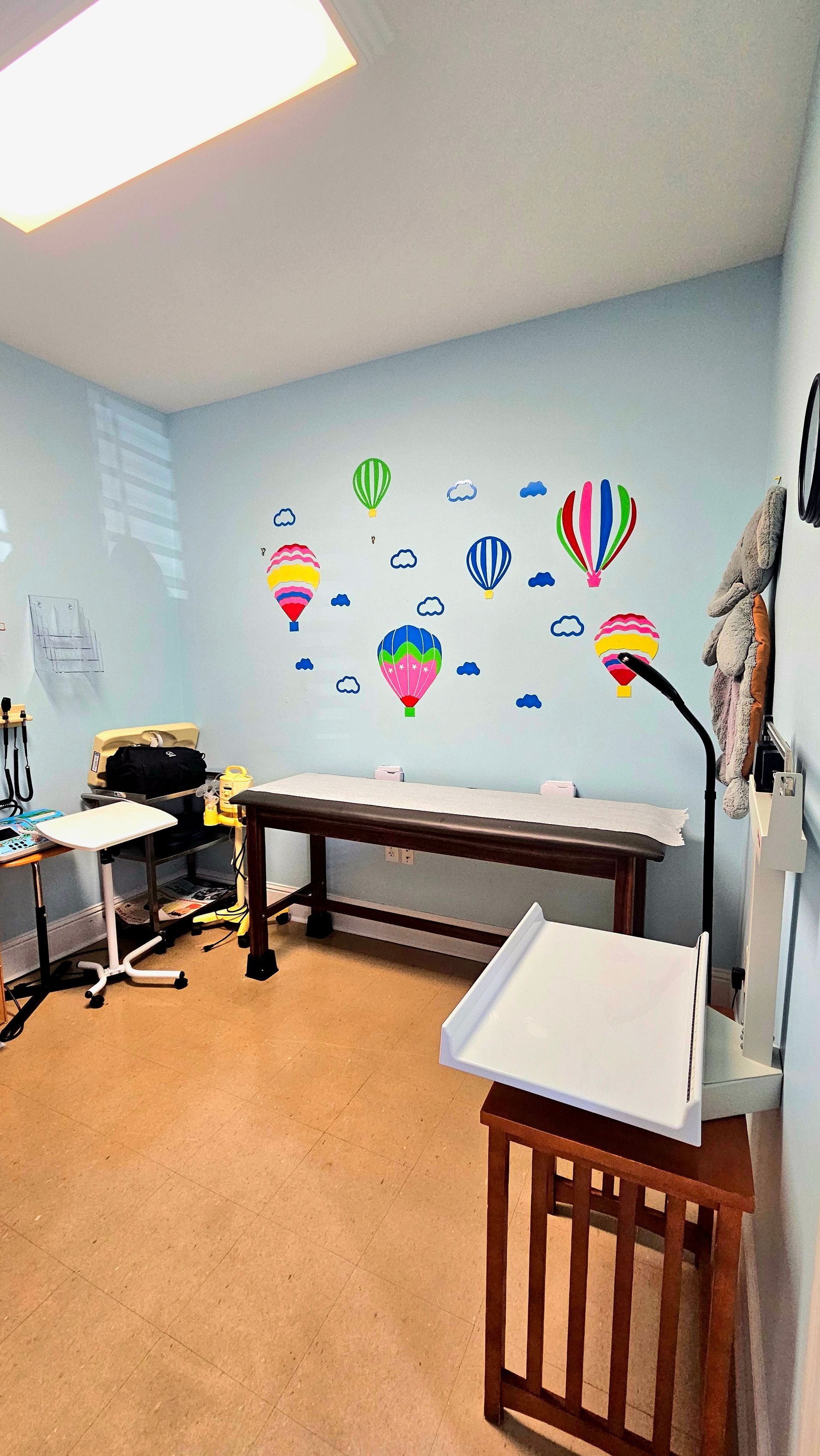 A room with blue walls decorated with hot air balloon decals, with tables and a lamp.
