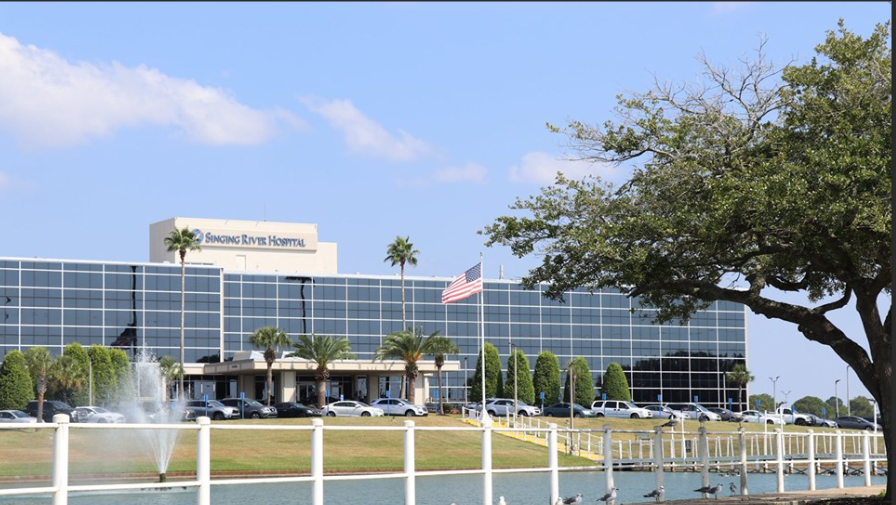 Modern multi-story building with glass and wood exterior under a blue sky.