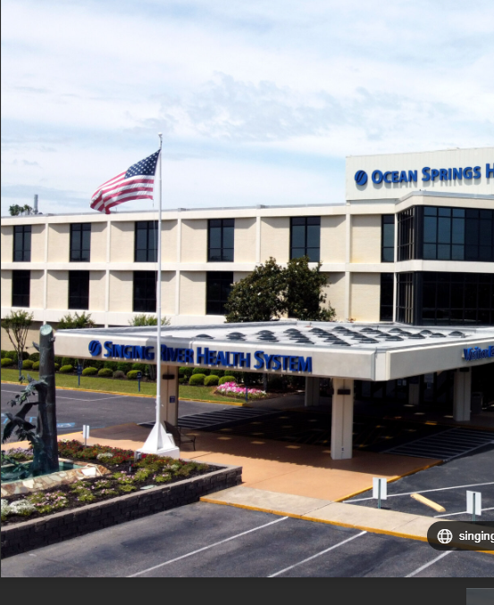 Modern multi-story building with glass and wood exterior under a blue sky.