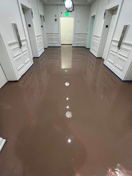 A long hallway with a brown floor and white walls.