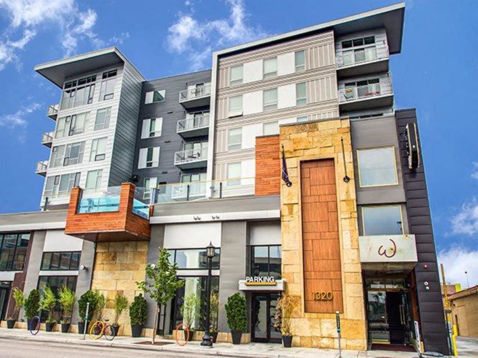 Modern multi-story apartment building exterior with balconies and stone accents against a blue sky at The Walkway, which offers apartments in Minneapolis, MN.