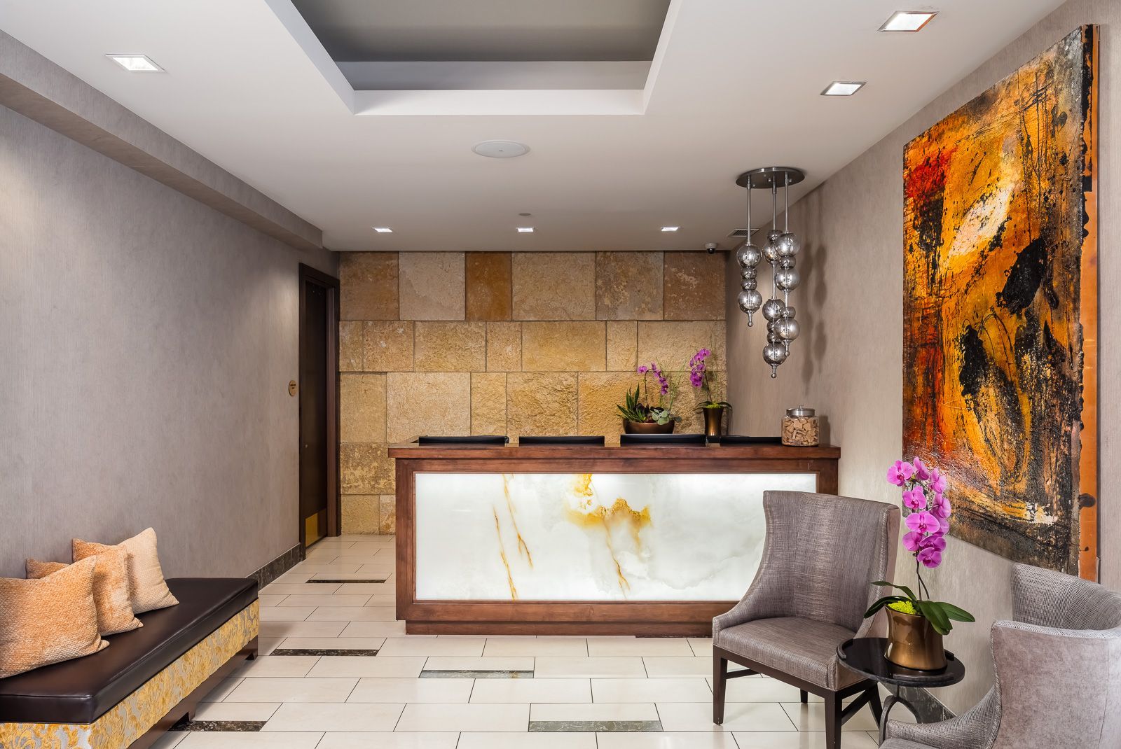 Interior lobby with a reception desk, seating area, stone wall, and wall art at The Walkway, which offers apartments near downtown Minneapolis.