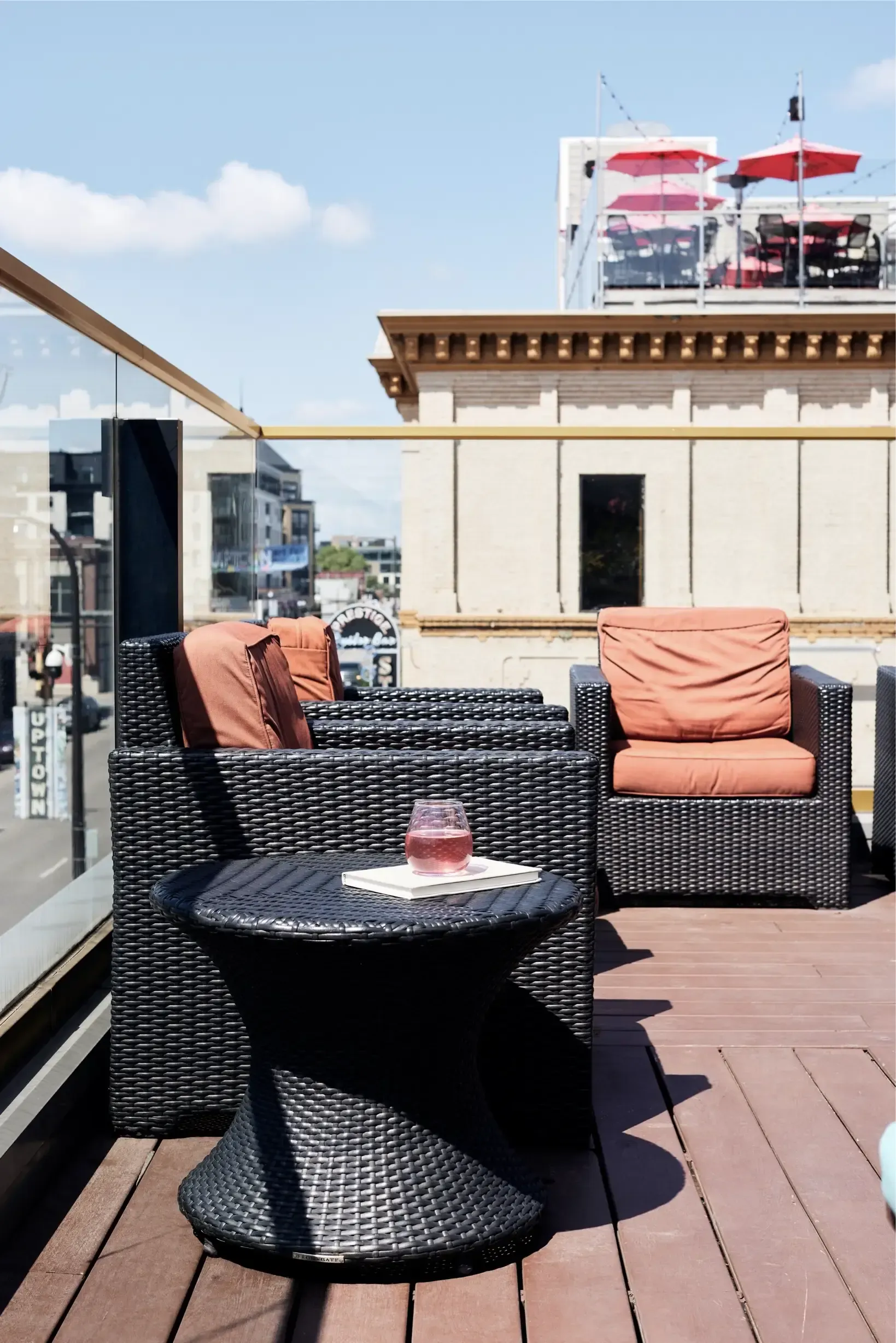 Rooftop outdoor seating on a terrace with wicker chairs and a small table holding a glass, cityscape behind at The Walkway, which offers apartments for rent in Minneapolis, MN.